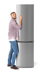 Photo of Young man hugging closed refrigerator on white background