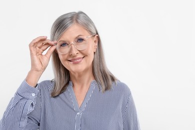 Portrait of beautiful senior woman in glasses on white background. Space for text