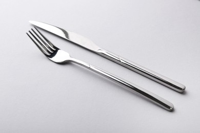 Photo of Stylish cutlery. Silver knife and fork on gray background