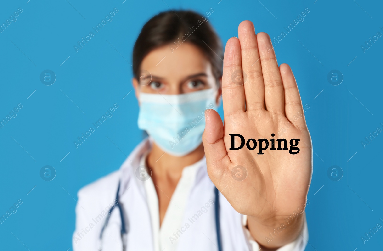 Image of Doctor in protective mask showing stop gesture against blue background, focus on hand. Doping control