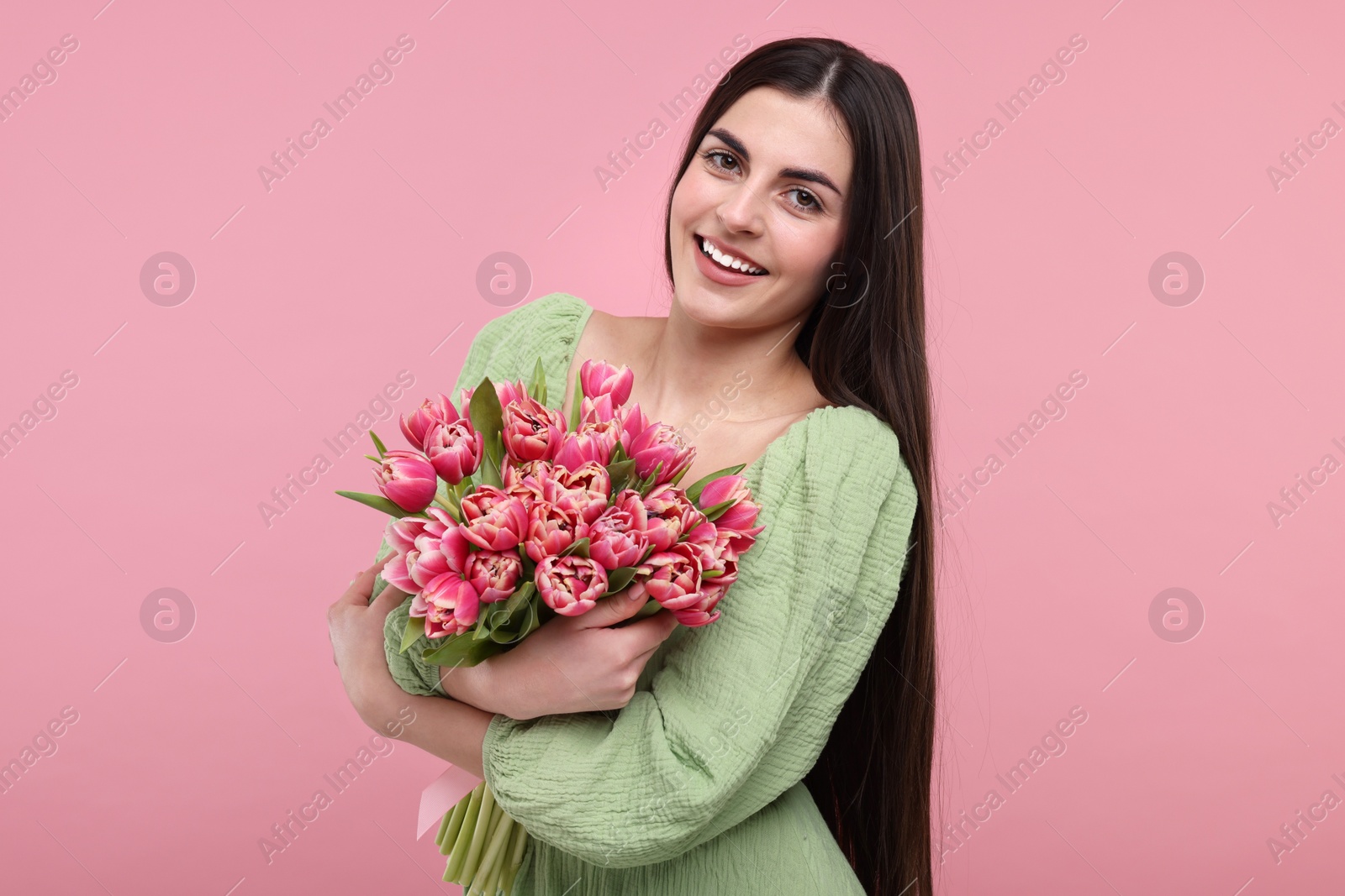 Photo of Happy young woman with beautiful bouquet on dusty pink background