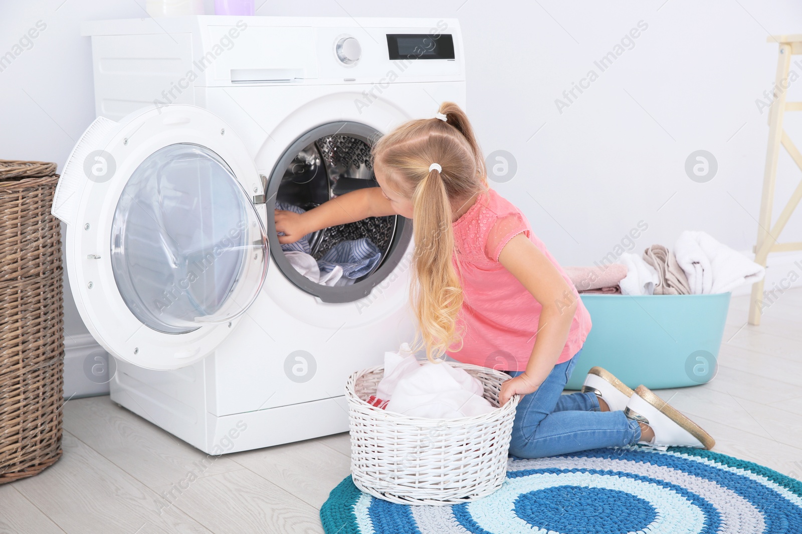 Photo of Adorable little girl doing laundry at home