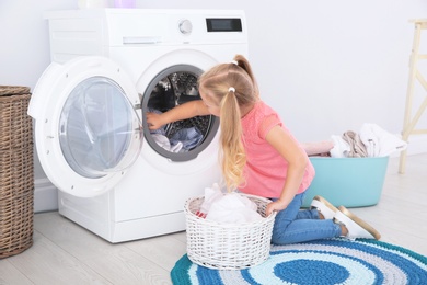 Photo of Adorable little girl doing laundry at home