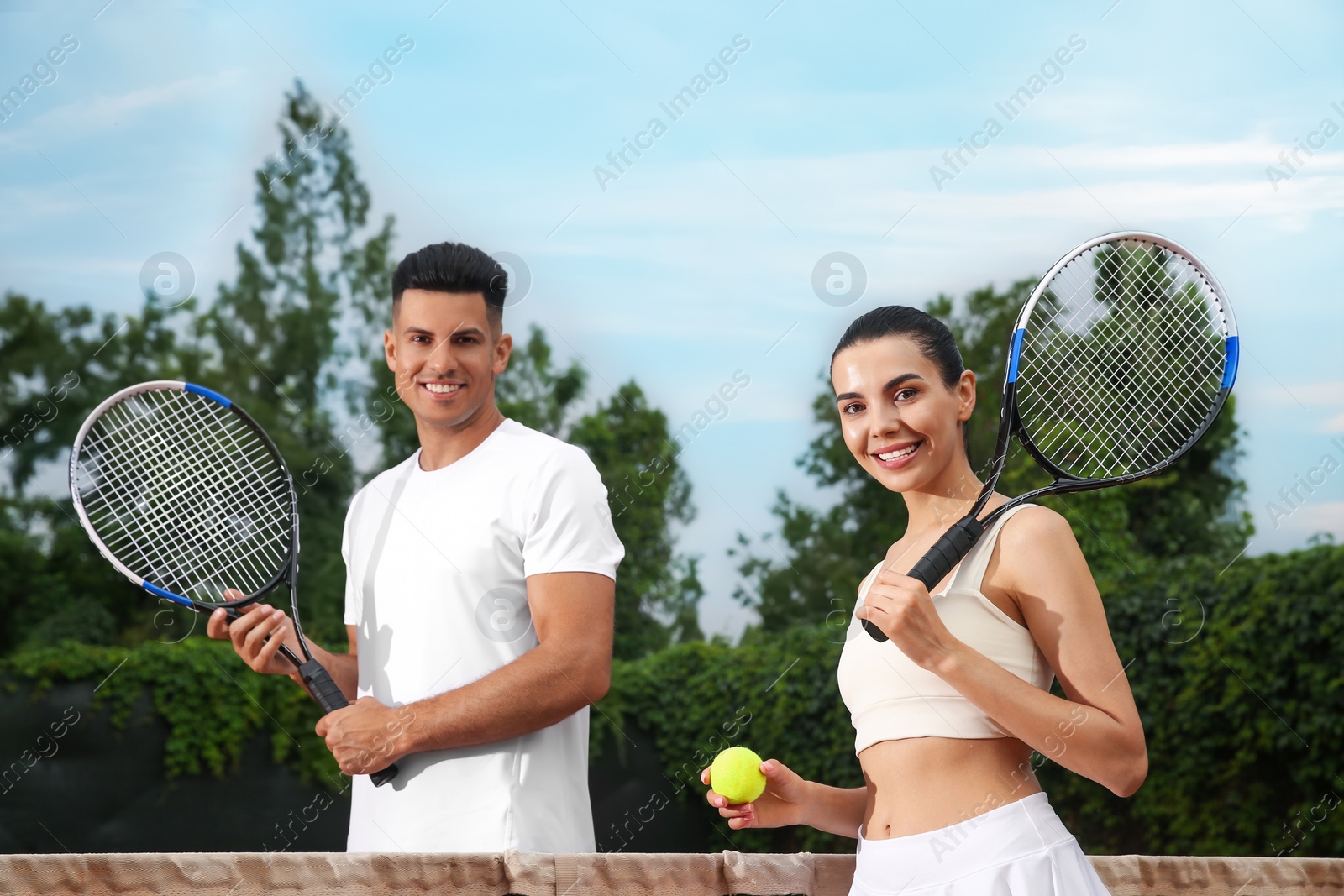 Photo of Couple with tennis rackets and ball at court