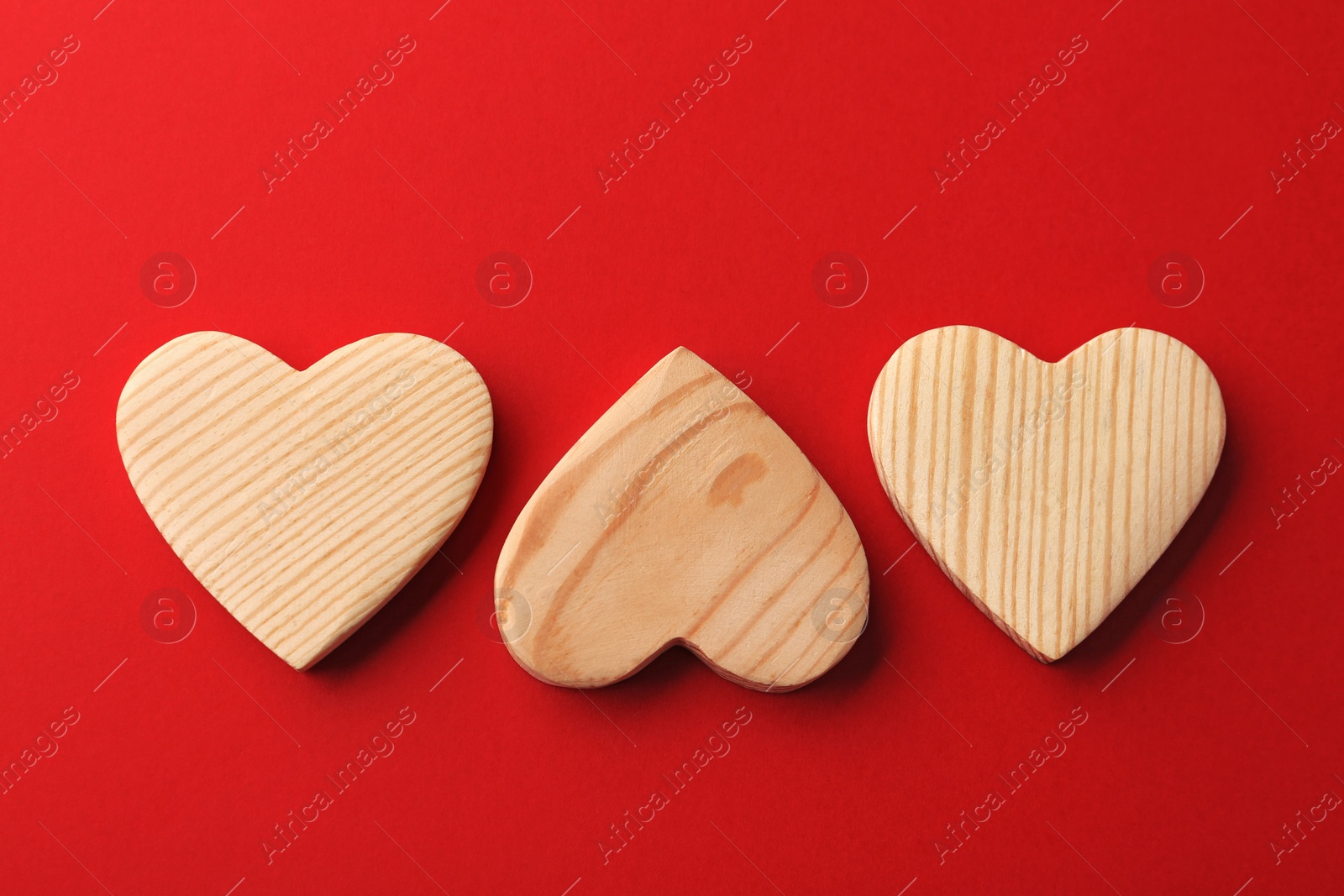 Photo of Wooden hearts on red background, flat lay