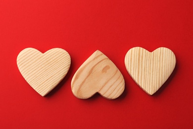 Wooden hearts on red background, flat lay