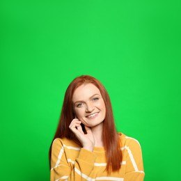 Image of Chroma key compositing. Happy young woman with red hair against green screen