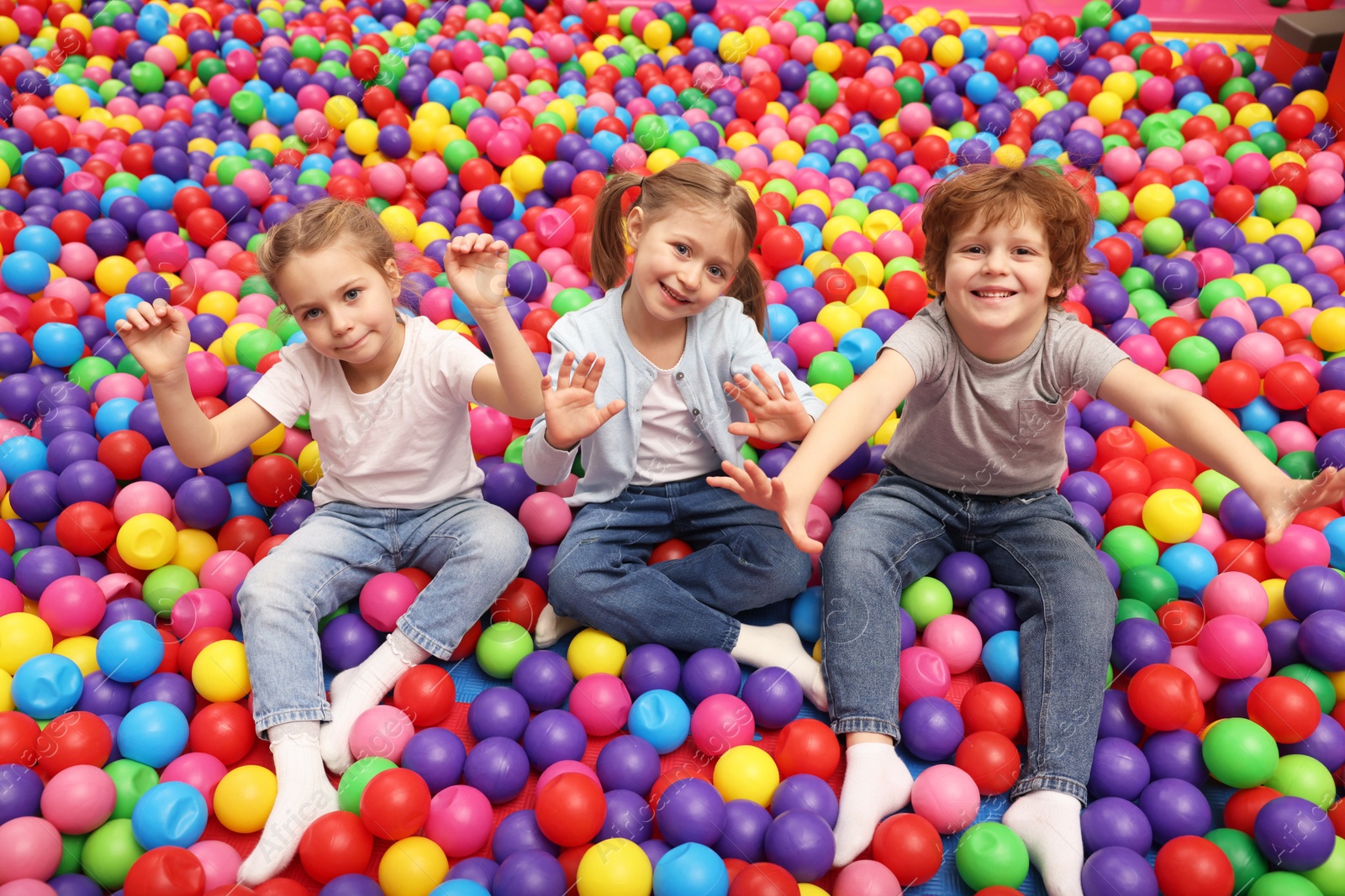 Photo of Happy little kids sitting on colorful balls in ball pit