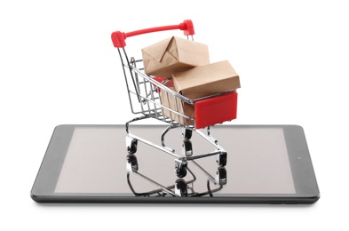 Photo of Internet shopping. Small cart with boxes and modern tablet on white background