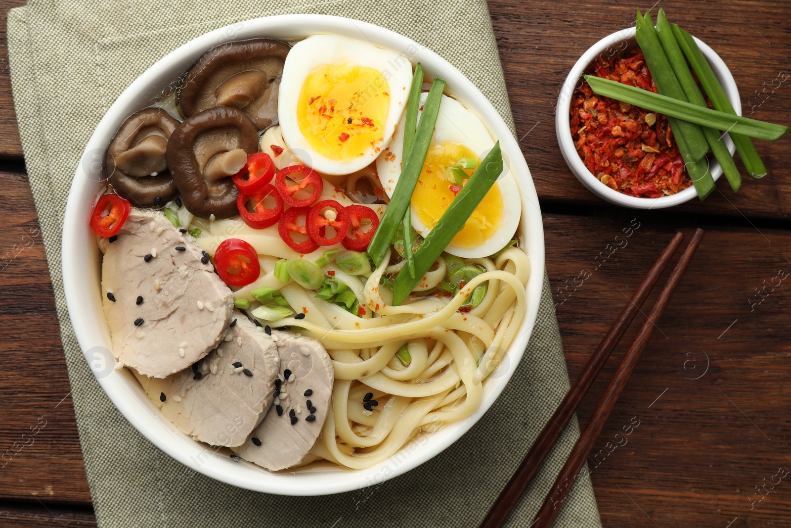 Photo of Delicious ramen with meat in bowl served on wooden table, flat lay. Noodle soup