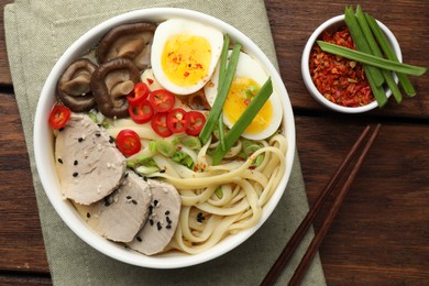 Delicious ramen with meat in bowl served on wooden table, flat lay. Noodle soup