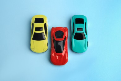 Photo of Different bright cars on light blue background, flat lay. Children`s toys