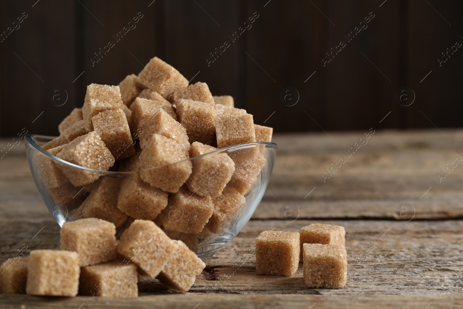 Photo of Brown sugar cubes on wooden table, closeup. Space for text