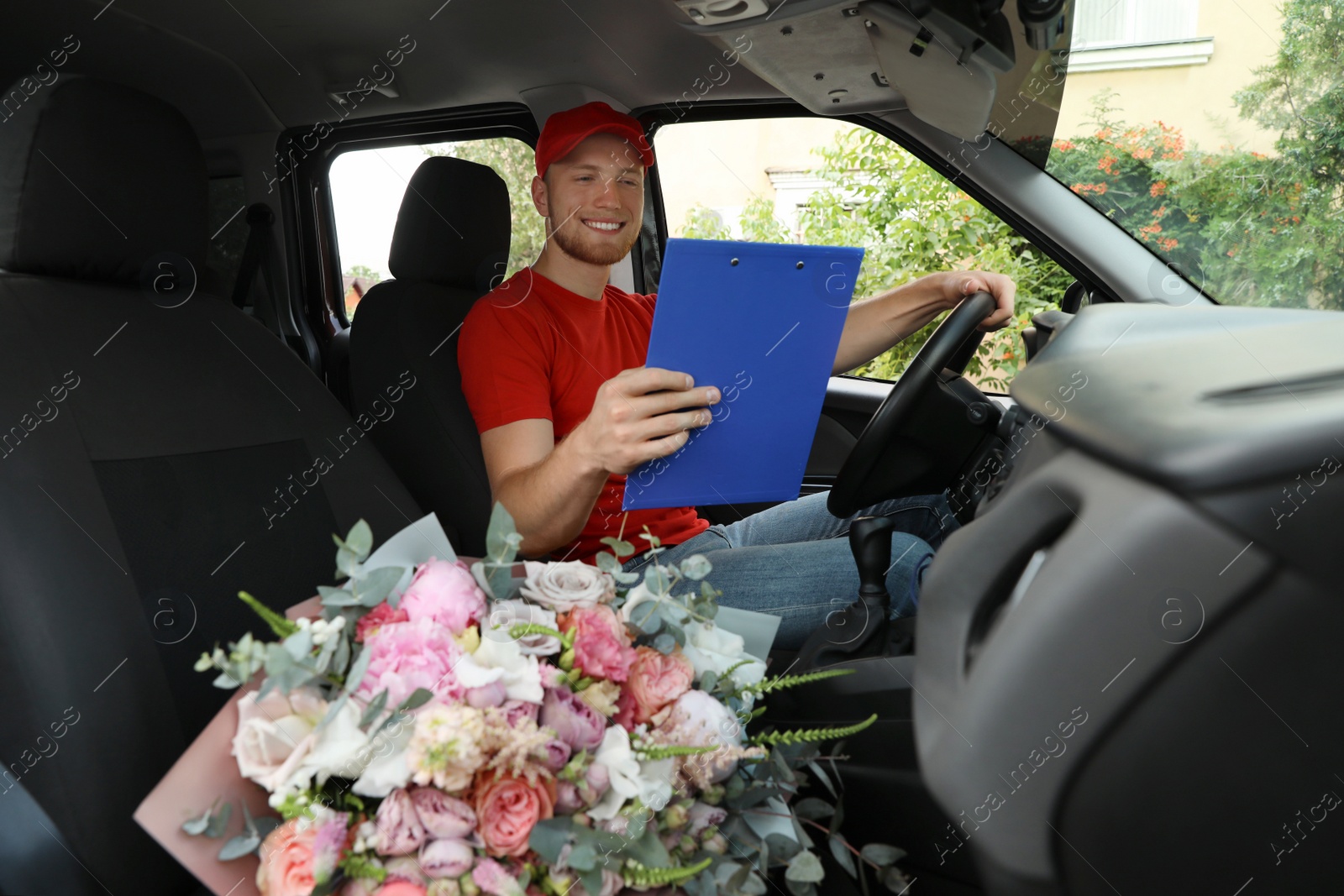 Photo of Delivery man with beautiful flower bouquet in car