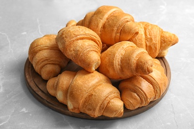 Photo of Wooden board with tasty croissants on table