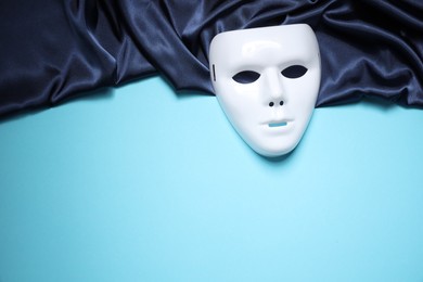 Theater arts. White mask and fabric on light blue background, top view. Space for text