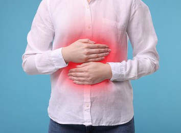Image of Woman suffering from stomach pain on light blue background, closeup