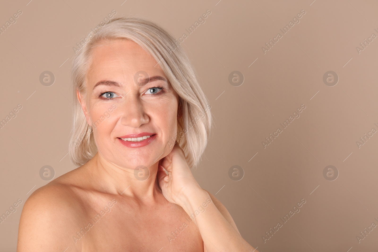 Photo of Portrait of charming mature woman with healthy beautiful face skin and natural makeup on beige background, space for text