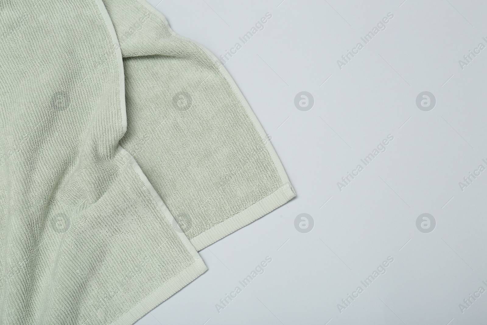 Photo of Soft green towel on light grey background, top view. Space for text