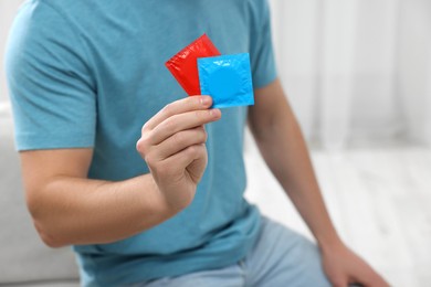 Closeup of man showing packs with condoms indoors. Space for text