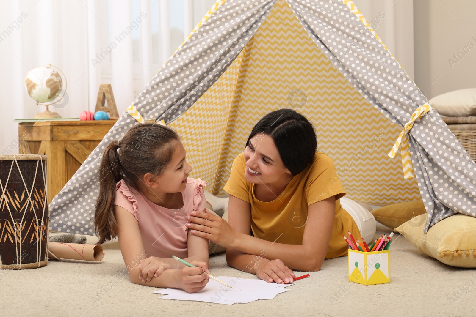 Photo of Mother and daughter drawing in wigwam at home