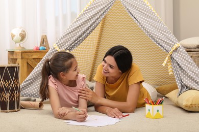Mother and daughter drawing in wigwam at home