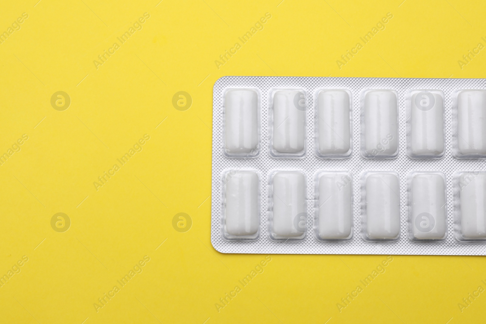 Photo of Blister with chewing gums on yellow background, top view. Space for text