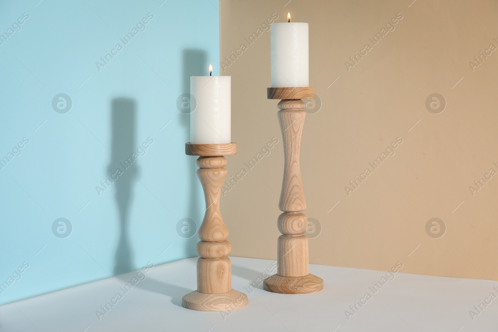 Photo of Elegant candlesticks with burning candles on white table