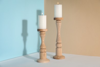 Elegant candlesticks with burning candles on white table
