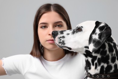 Photo of Beautiful woman with her adorable Dalmatian dog on light grey background, selective focus. Lovely pet