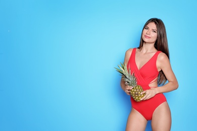 Photo of Sexy young woman in bikini with pineapple on color background