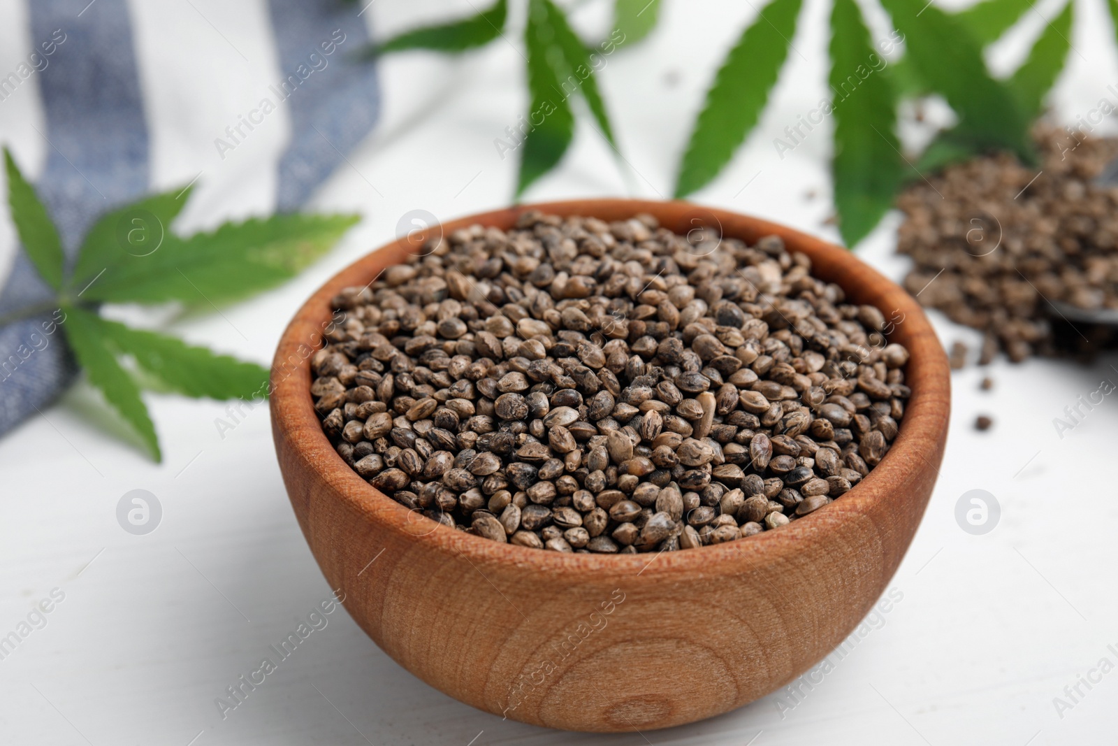 Photo of Bowl with hemp seeds on white wooden table