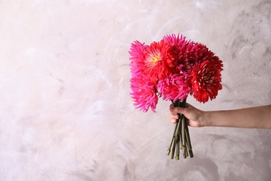 Photo of Woman holding beautiful dahlia flowers on color background. Space for text