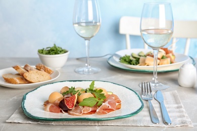 Plate with melon balls and prosciutto served on gray table