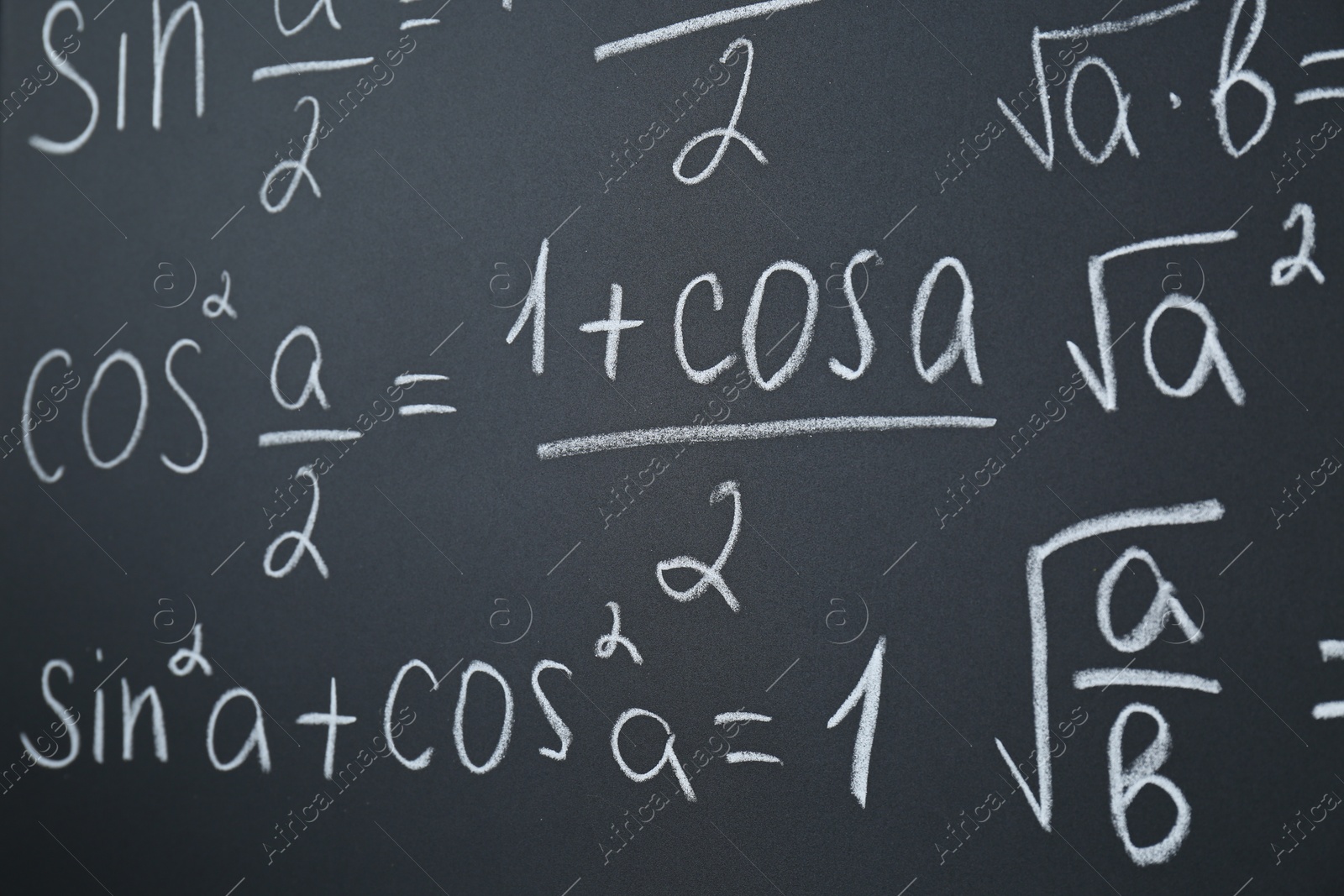 Photo of Different mathematical formulas written with chalk on blackboard, closeup