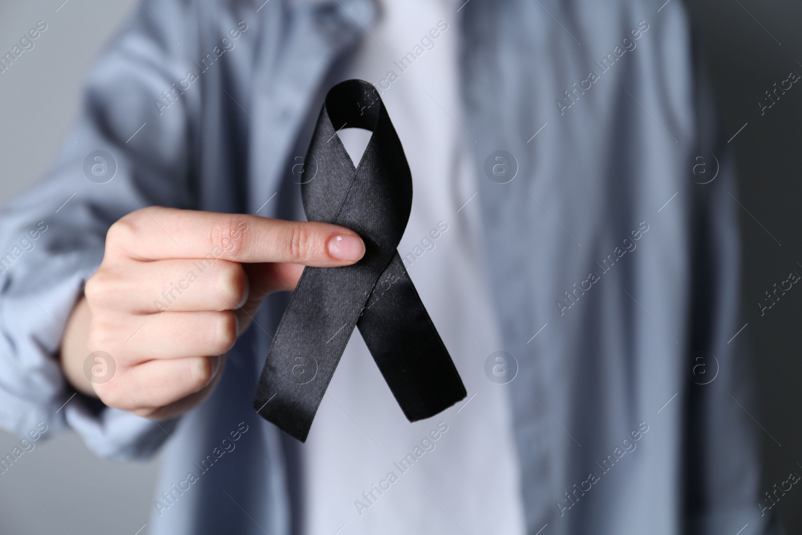 Photo of Woman holding black awareness ribbon, closeup view