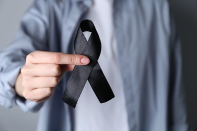 Woman holding black awareness ribbon, closeup view