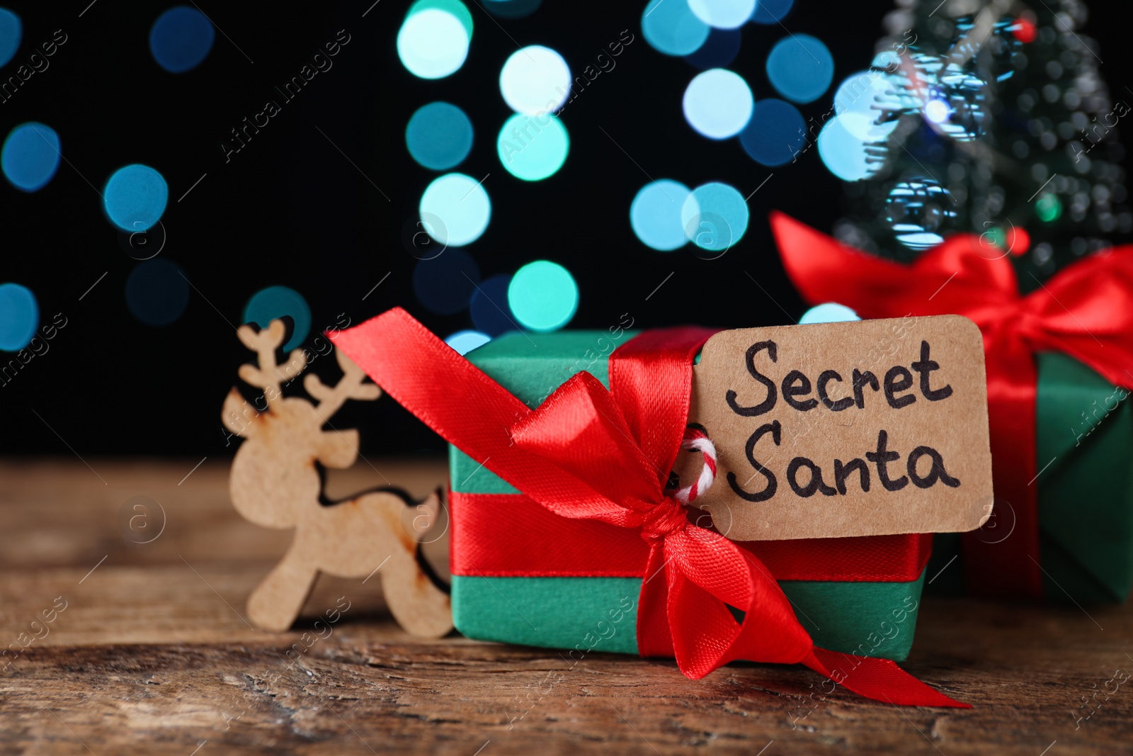 Photo of Present from secret Santa on wooden table against blurred lights
