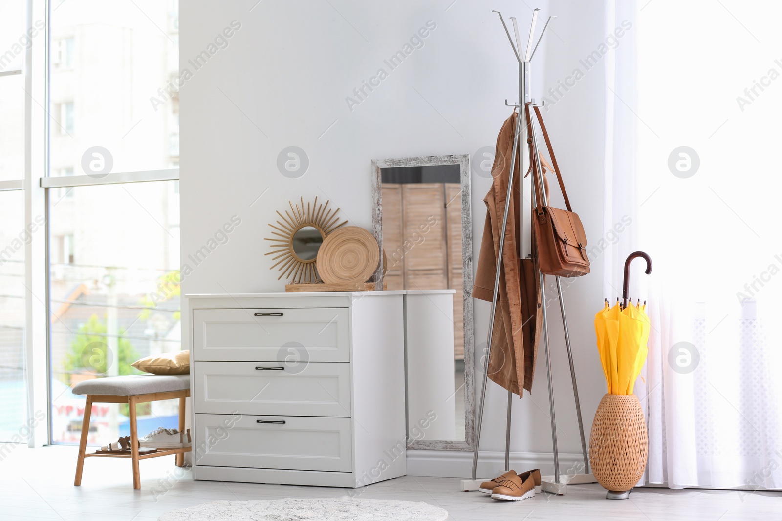 Photo of Modern hallway interior with chest of drawers and clothes on hanger stand