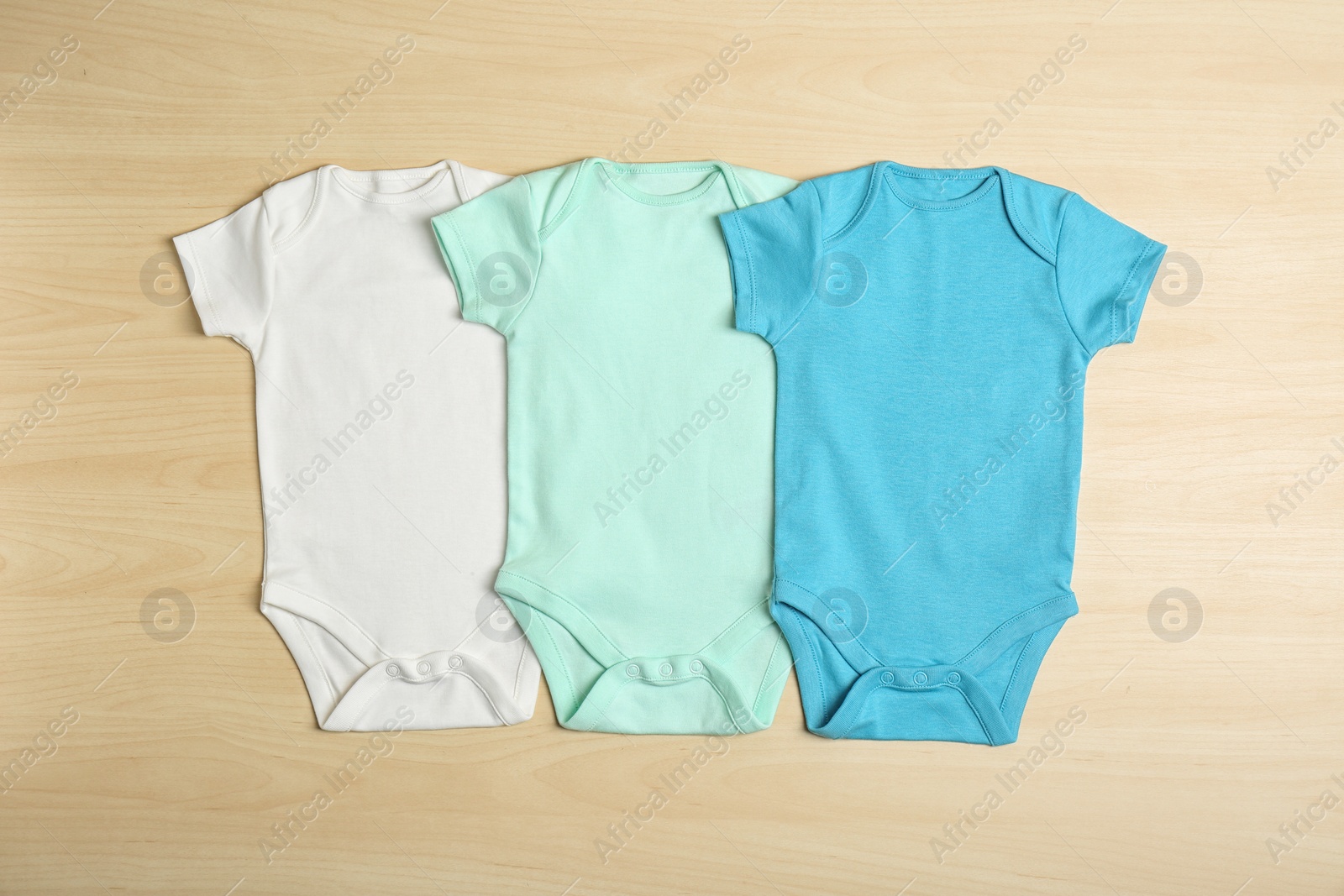 Photo of Different baby bodysuits on wooden background, top view