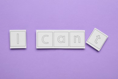 Photo of Motivation concept. Changing phrase from I Can't into I Can by removing paper with letter T on violet background, top view