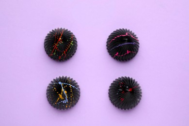 Photo of Tasty chocolate candies on violet background, flat lay