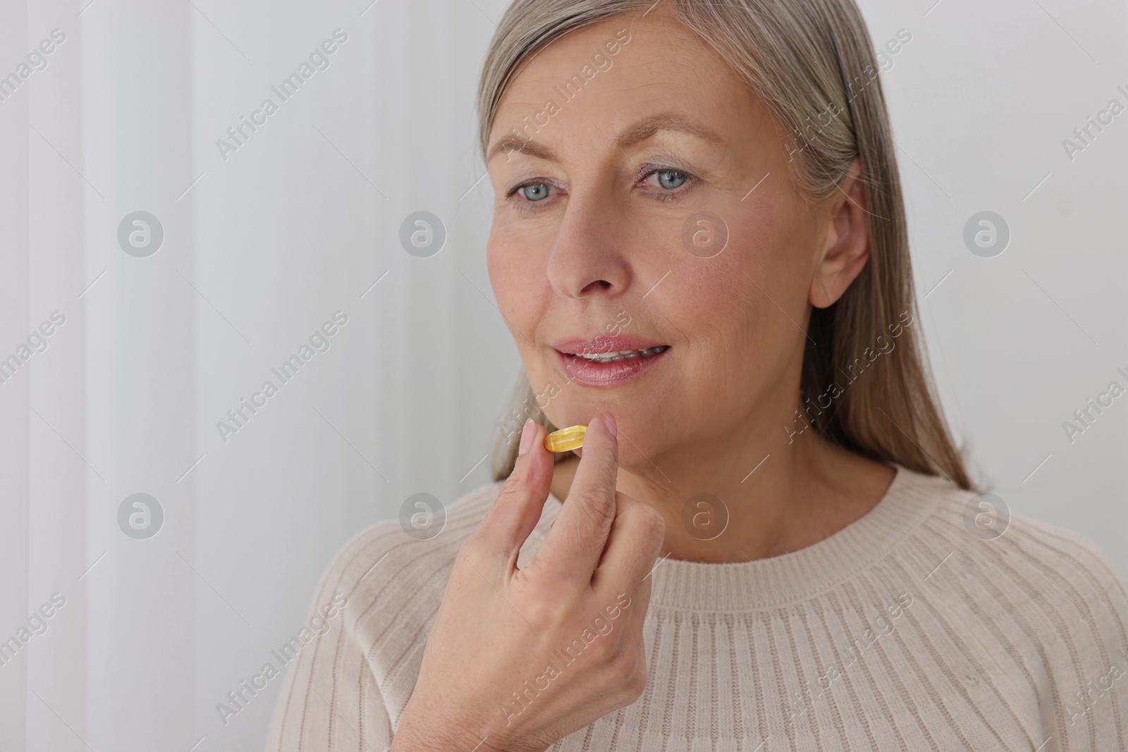 Photo of Beautiful woman taking vitamin pill at home