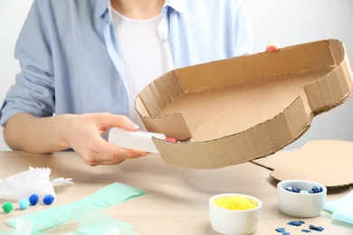 Woman making cardboard cloud at wooden table, closeup. Pinata diy