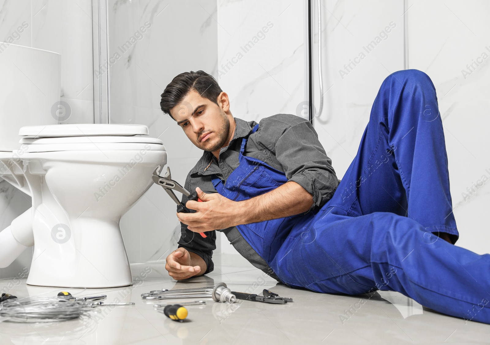 Photo of Professional plumber working with toilet bowl in bathroom