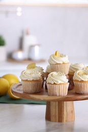 Photo of Delicious lemon cupcakes with white cream on table indoors