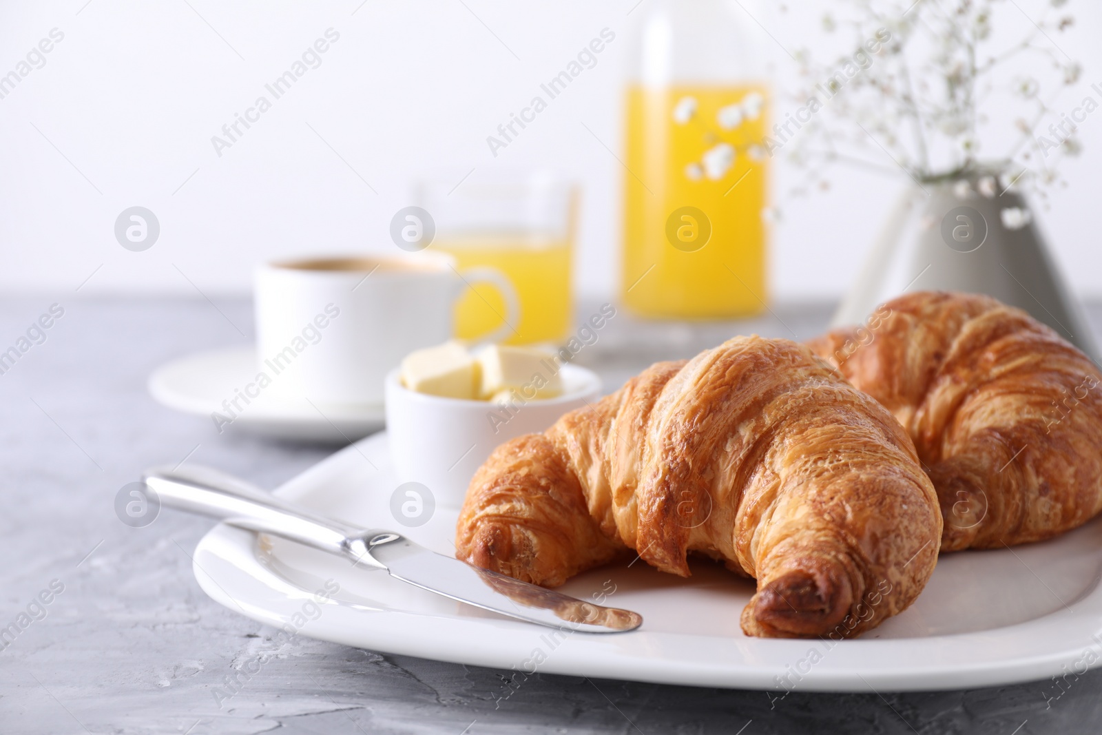 Photo of Tasty breakfast. Fresh croissants and butter on grey table, closeup