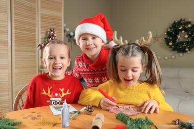 Cute little children making beautiful Christmas greeting cards at home