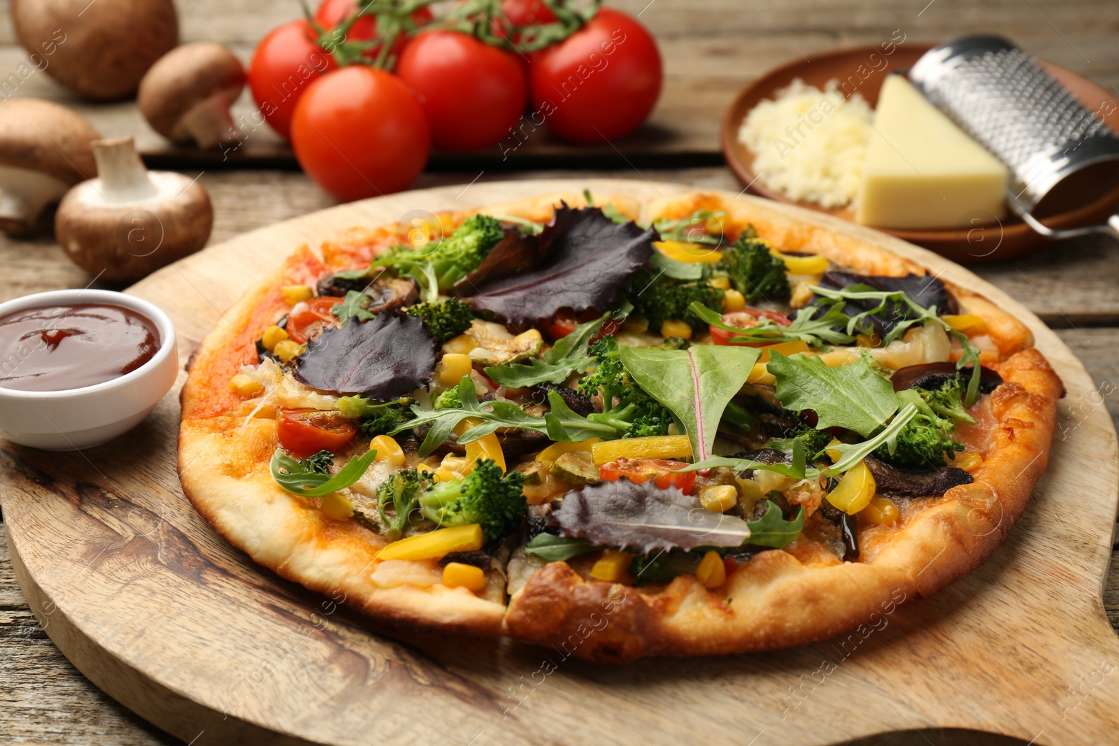 Photo of Delicious vegetarian pizza and ingredients on wooden table, closeup