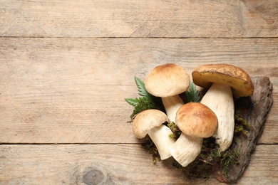 Flat lay composition with porcini mushrooms on wooden table, space for text